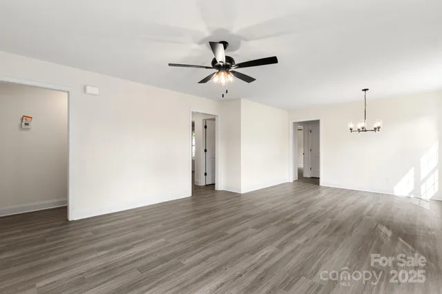 an empty room with wooden floor ceiling fan and window
