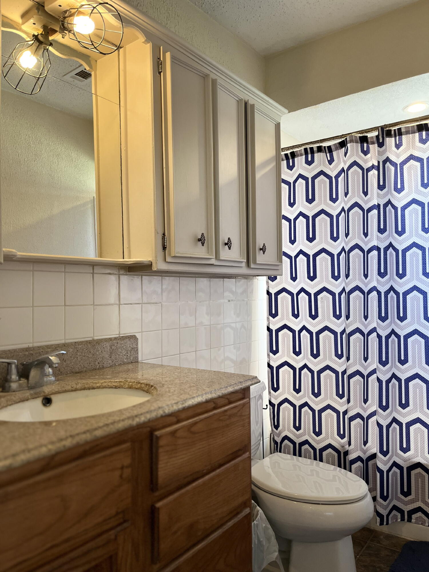 1724 28th Street Lubbock, TX 79411 - Photo 15 of 26 a bathroom with a toilet a sink and a shower curtain