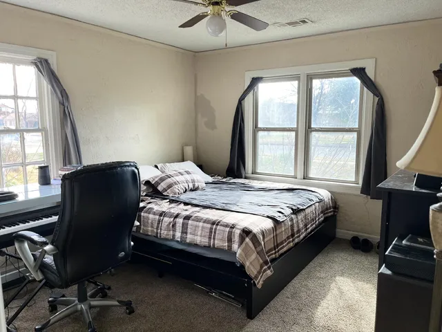 a bedroom with a bed a couch and a ceiling fan