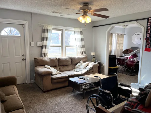 a living room with furniture a ceiling fan and a window