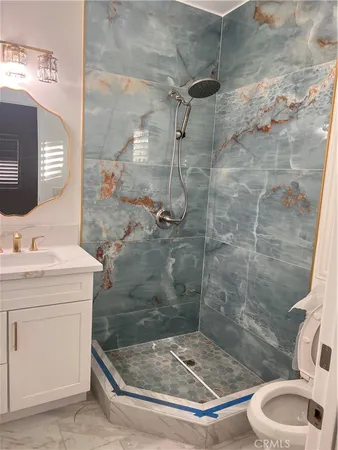 a bathroom with a granite countertop sink a toilet and shower