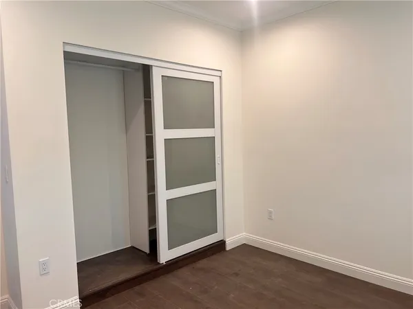 an empty room with wooden floor closet and windows