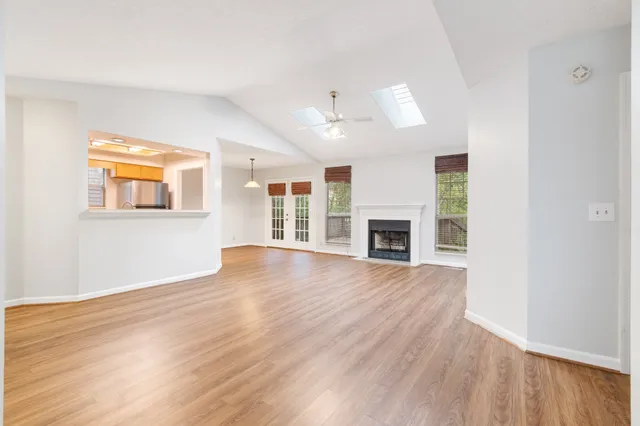 a view of an empty room with wooden floor fireplace and a window