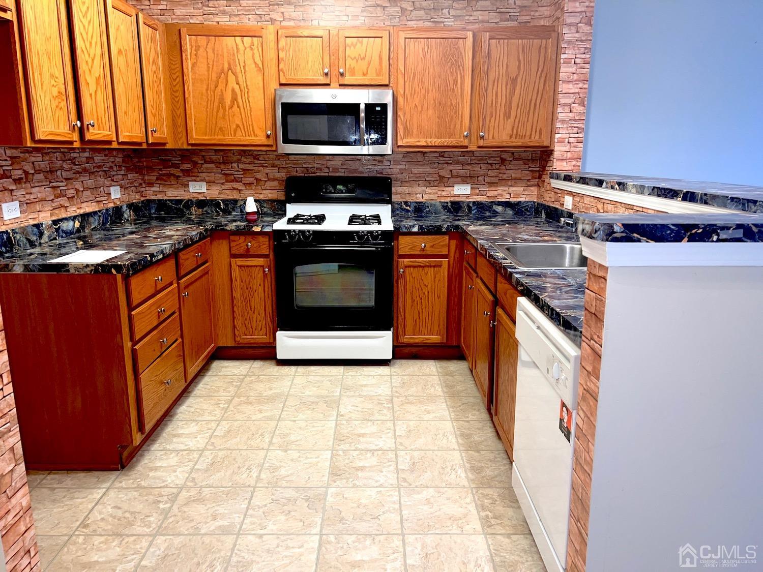368 Rector Street, Unit 317 Perth Amboy, NJ 08861 - Photo 4 of 25 Loads of oak cabinets in the kitchen. Gas top stove with microwave above. Dishwasher and SS sink.