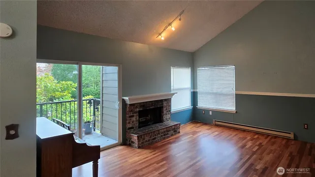 a view of wooden floor fire place and windows in a room