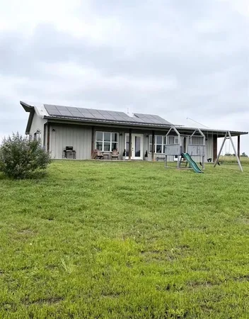 a view of a house with a big yard and large trees
