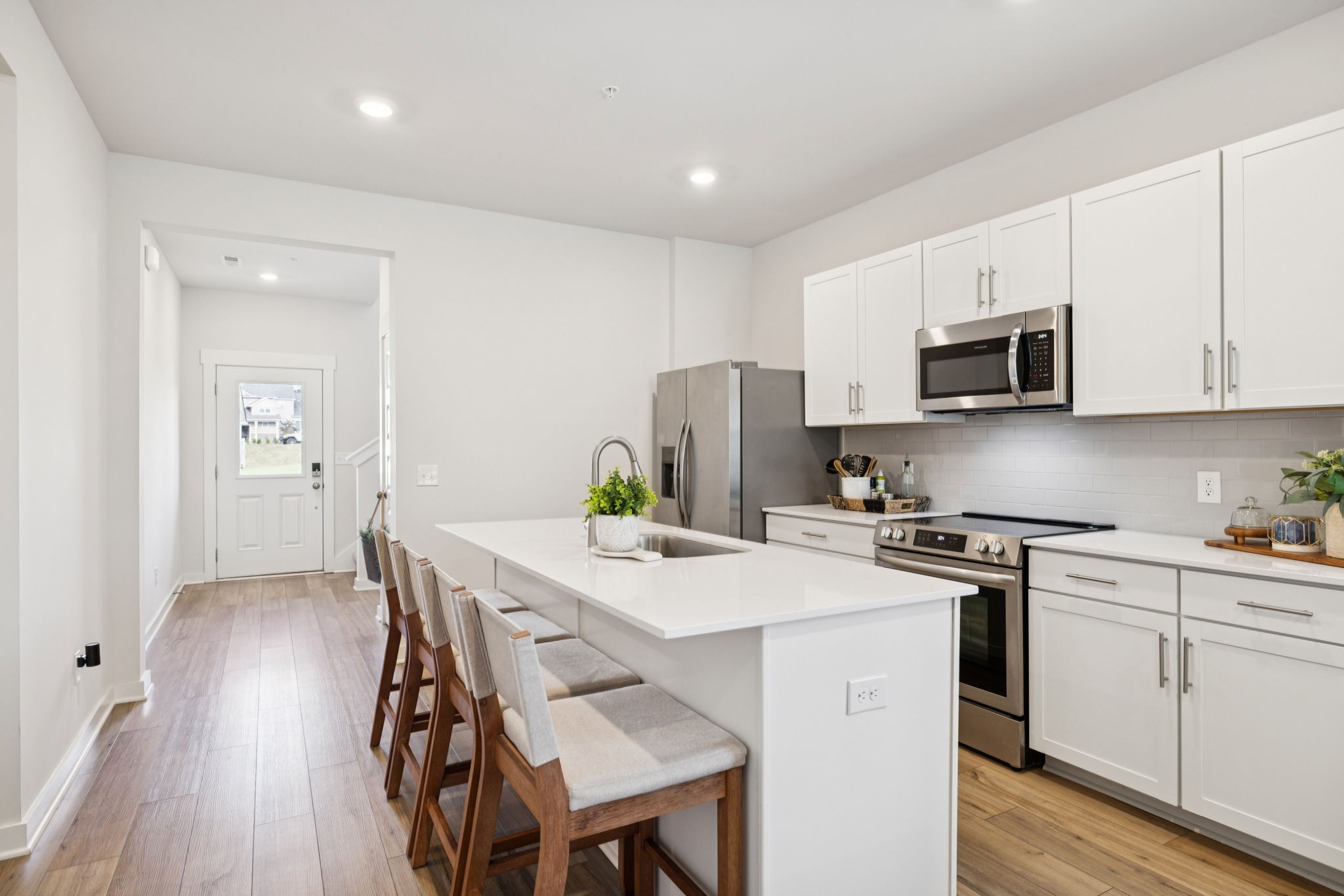 647 Birdie Drive Spring Hill, TN 37174 - Photo 3 of 15 a kitchen with stainless steel appliances a stove a sink a microwave a refrigerator white cabinets and wooden floor