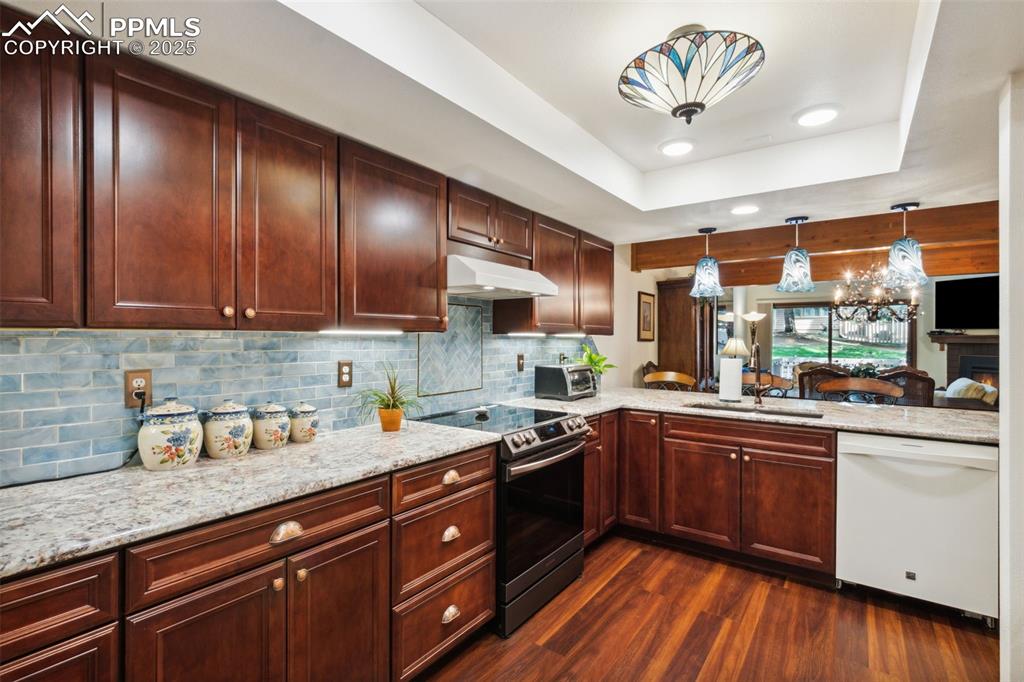 4835 Castledown Road Colorado Springs, CO 80917 - Photo 8 of 29 a kitchen with stainless steel appliances granite countertop wooden cabinets a sink a stove a dining table and chairs