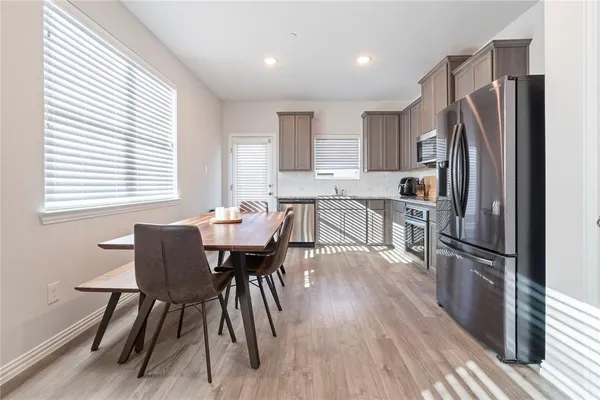 a kitchen with stainless steel appliances a dining table chairs a refrigerator and cabinets