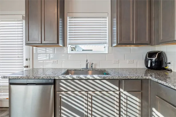 a kitchen with granite countertop a sink window and cabinets