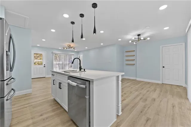a kitchen with kitchen island a sink stainless steel appliances and cabinets