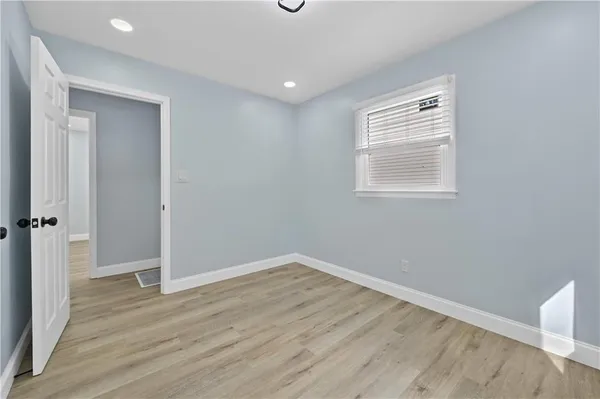 an empty room with wooden floor closet and windows