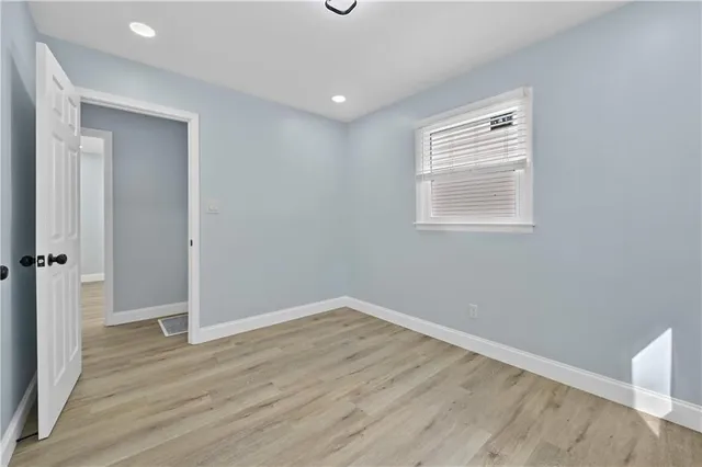 an empty room with wooden floor closet and windows