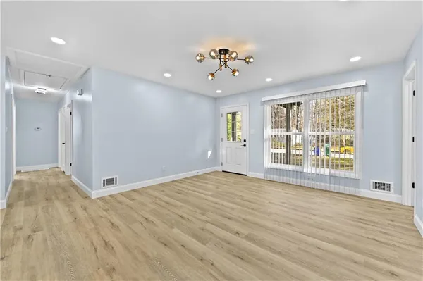 a view of an empty room with a window and wooden floor