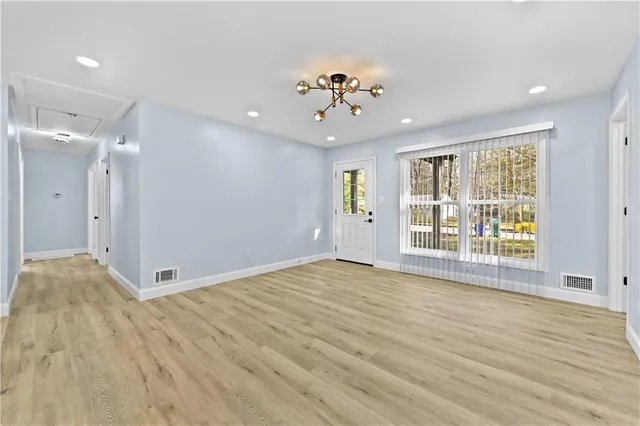 a view of an empty room with a window and wooden floor
