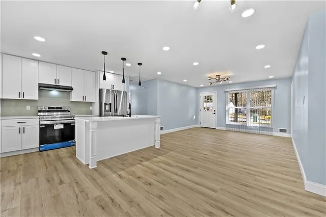 a large kitchen with stainless steel appliances granite countertop a large counter top a stove and a wooden floors