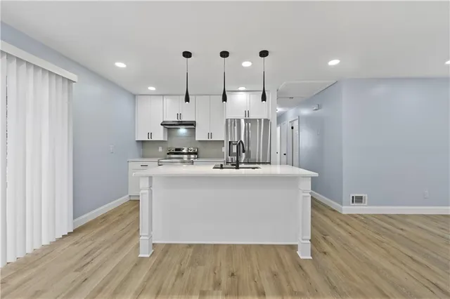 a view of kitchen with stainless steel appliances granite countertop cabinets and wooden floor