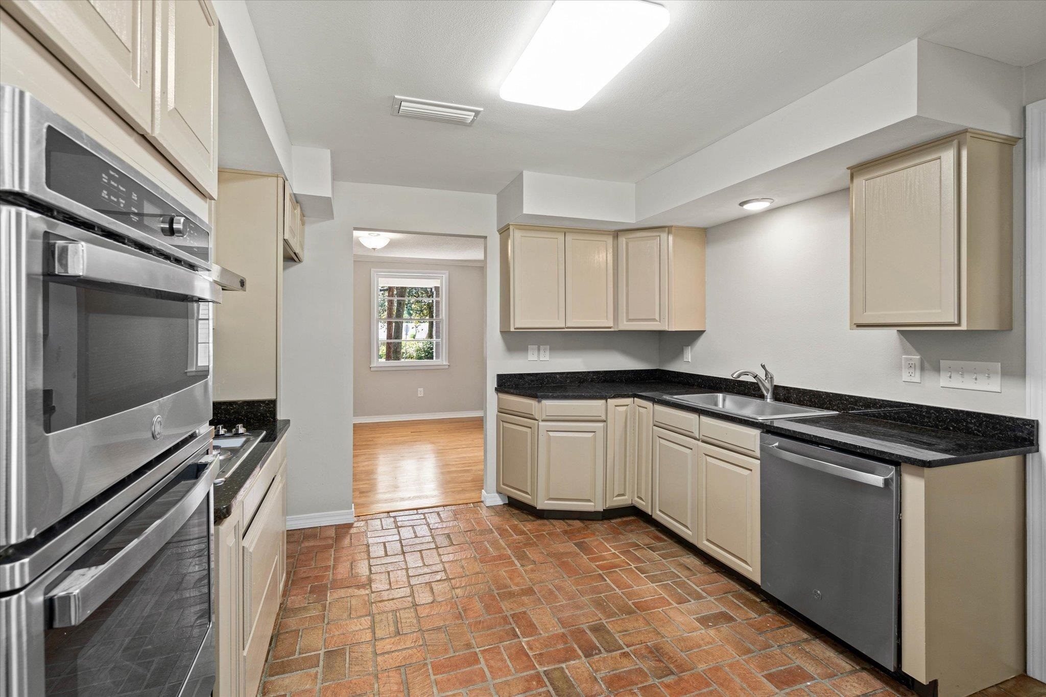 4700 Bit And Spur Road Mobile, AL 36608 - Photo 9 of 21 Kitchen with a sink, brick floor, cream cabinets, stainless steel appliances, and baseboards