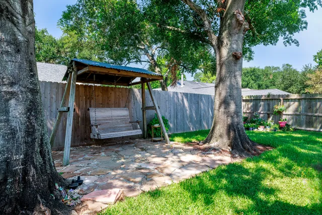 a view of a patio with table and chairs potted plants and large tree