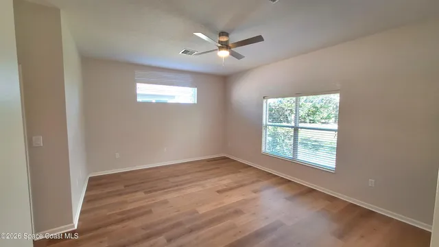 an empty room with wooden floor and windows