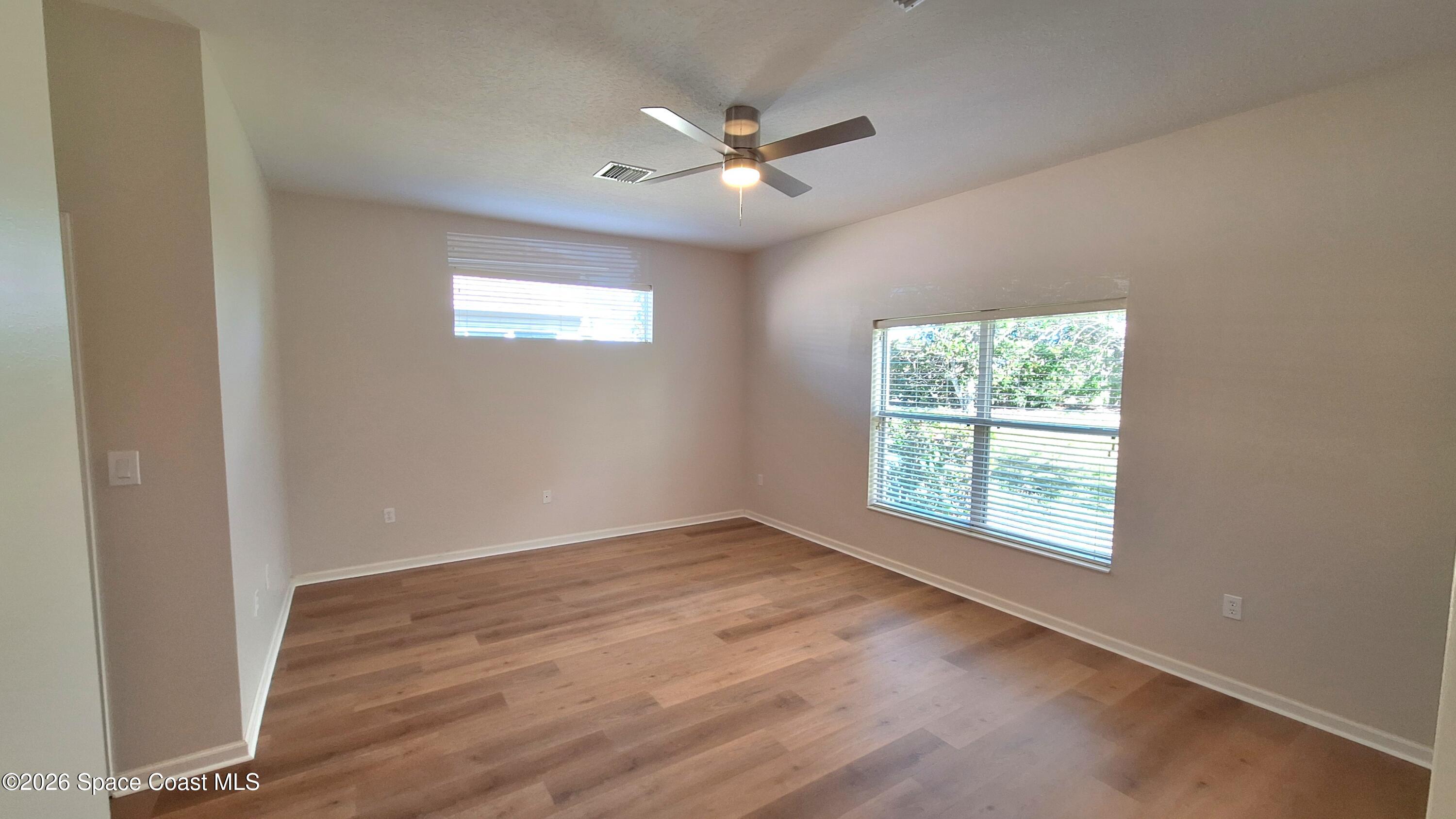 6921 Abbeyville Road Melbourne, FL 32940 - Photo 13 of 24 an empty room with wooden floor and windows