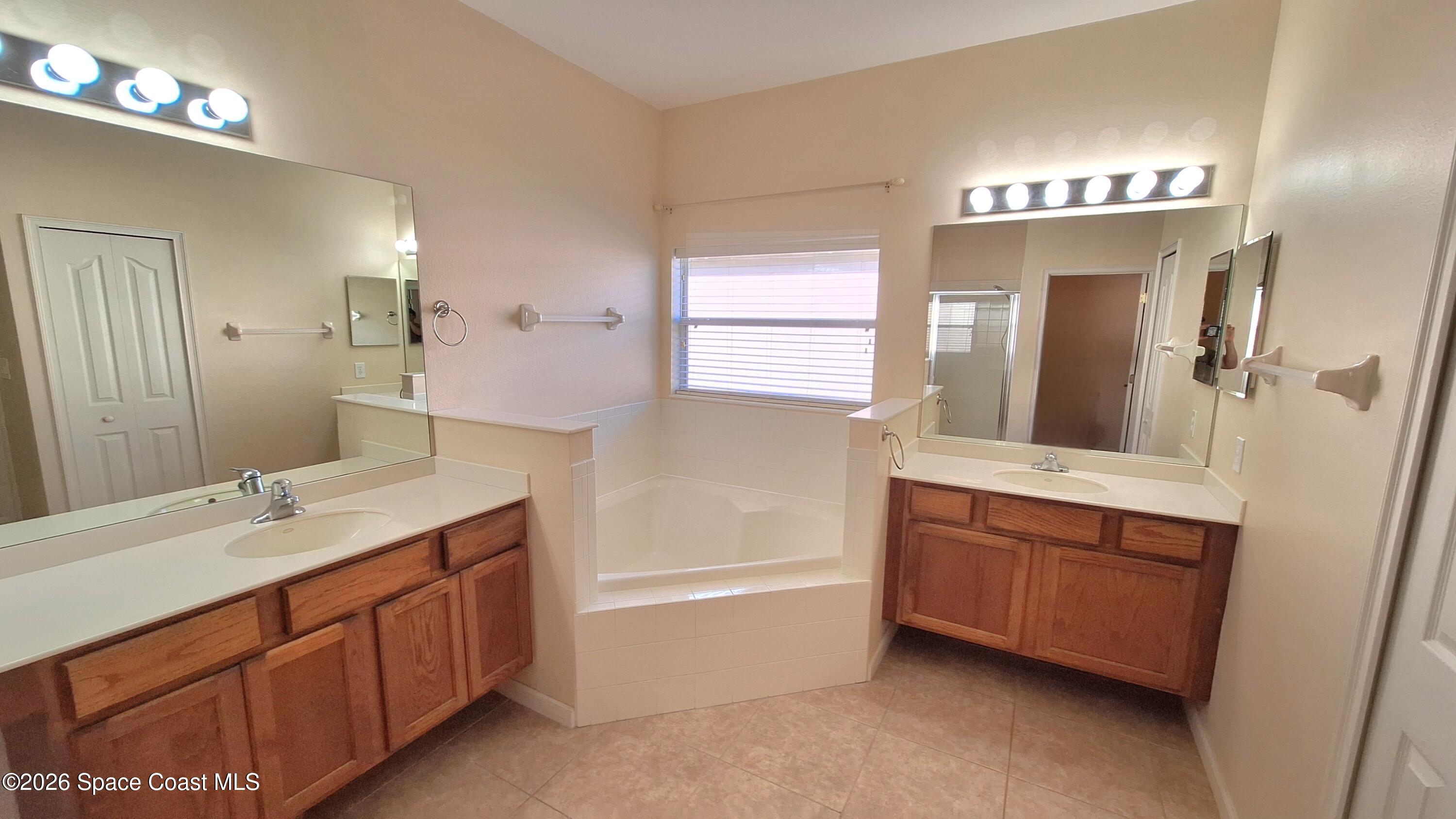 6921 Abbeyville Road Melbourne, FL 32940 - Photo 15 of 24 a spacious bathroom with a double vanity sink a mirror and a bathtub