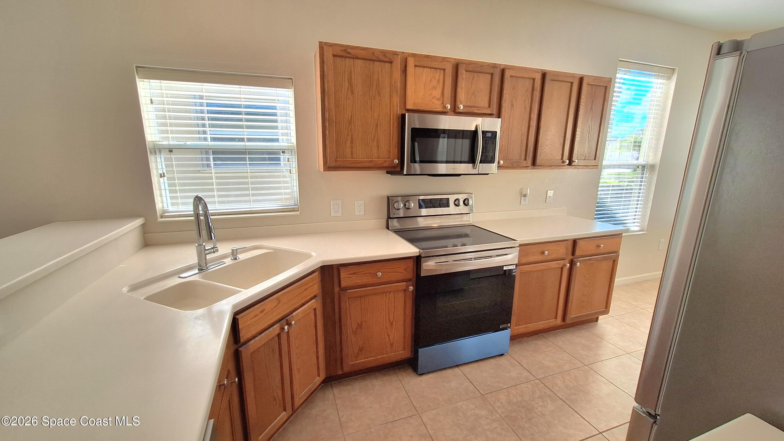 6921 Abbeyville Road Melbourne, FL 32940 - Photo 5 of 24 a kitchen with stainless steel appliances granite countertop a sink stove and microwave