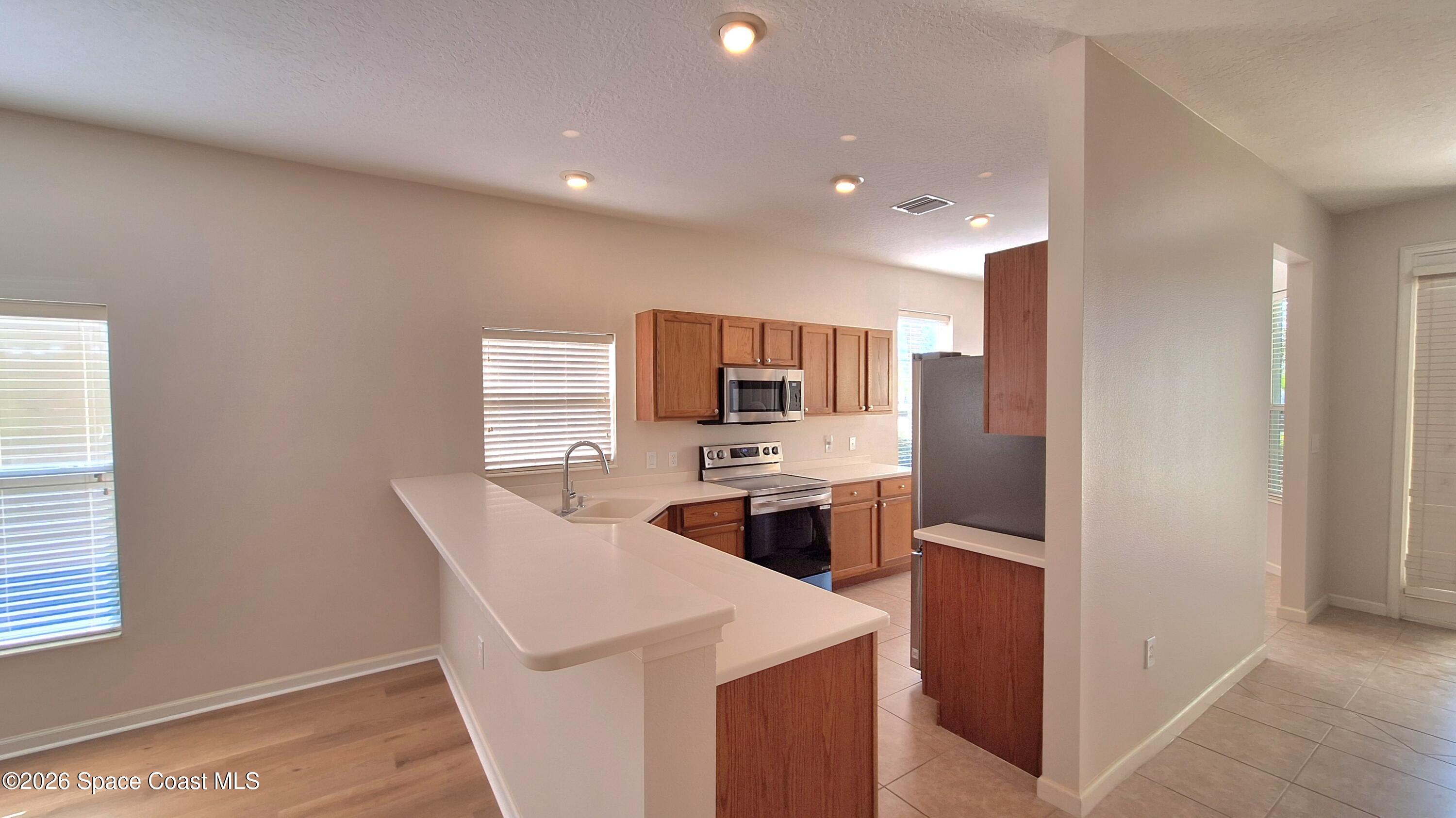 6921 Abbeyville Road Melbourne, FL 32940 - Photo 6 of 24 a kitchen with stainless steel appliances kitchen island granite countertop a refrigerator and a stove top oven
