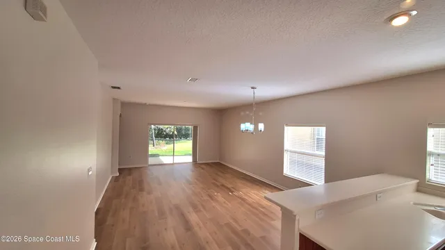a view of empty room with window and wooden floor
