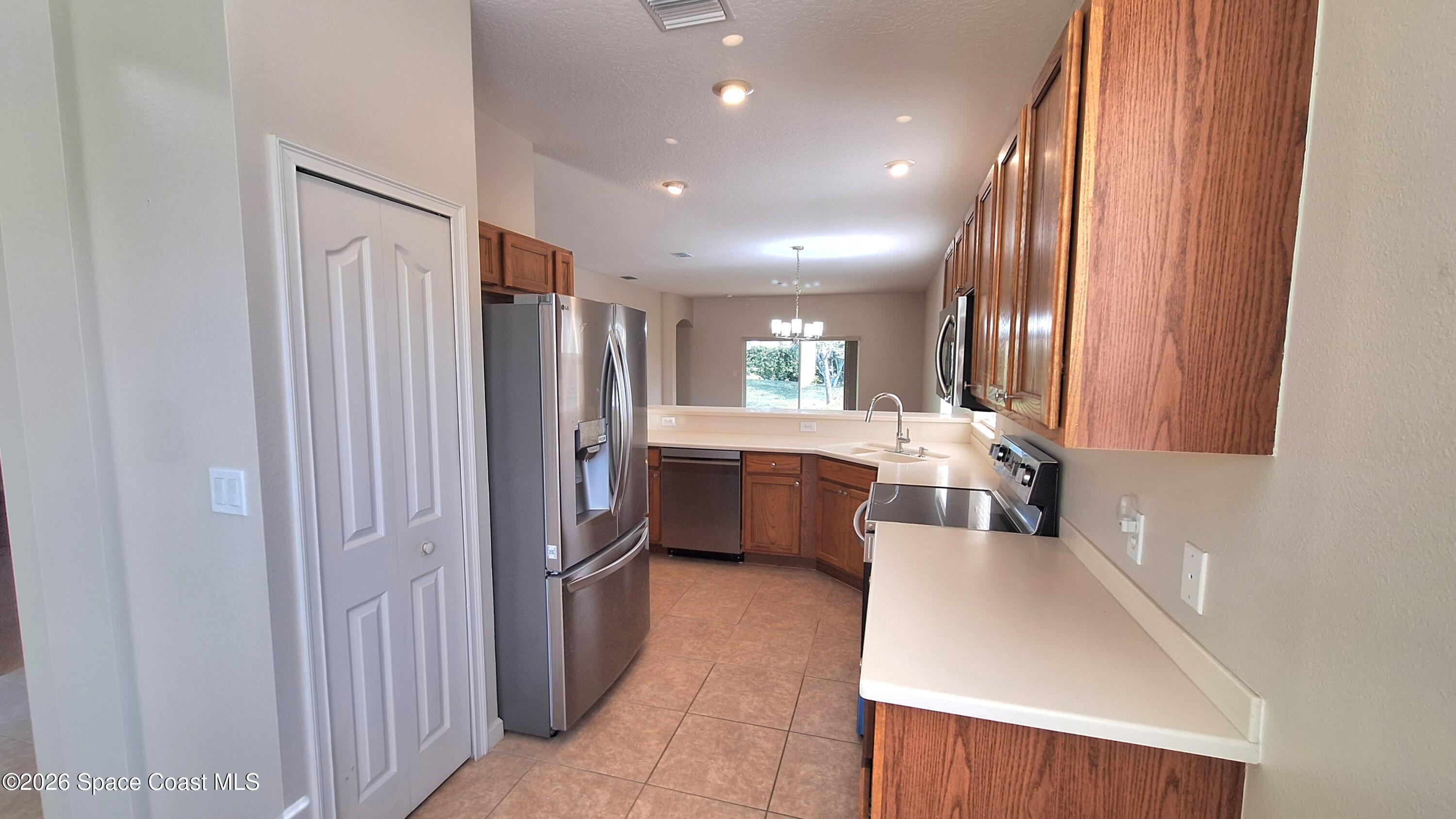 6921 Abbeyville Road Melbourne, FL 32940 - Photo 9 of 24 a kitchen with refrigerator a sink and cabinets