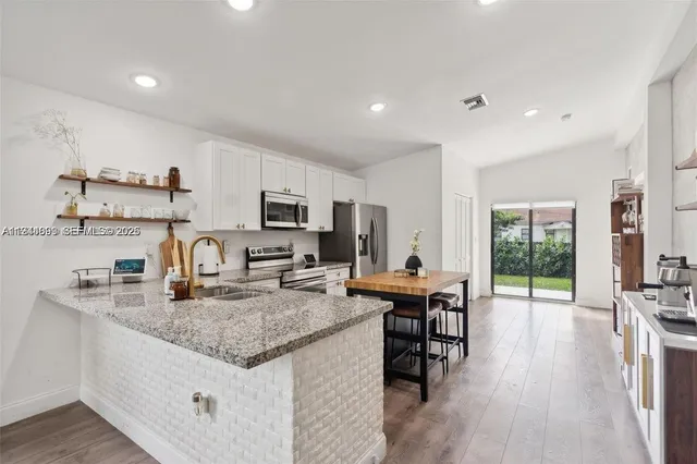 a kitchen with stainless steel appliances granite countertop sink stove top oven and cabinets