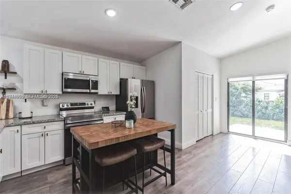 a kitchen with a stove a sink dishwasher a refrigerator with a dining table and chairs