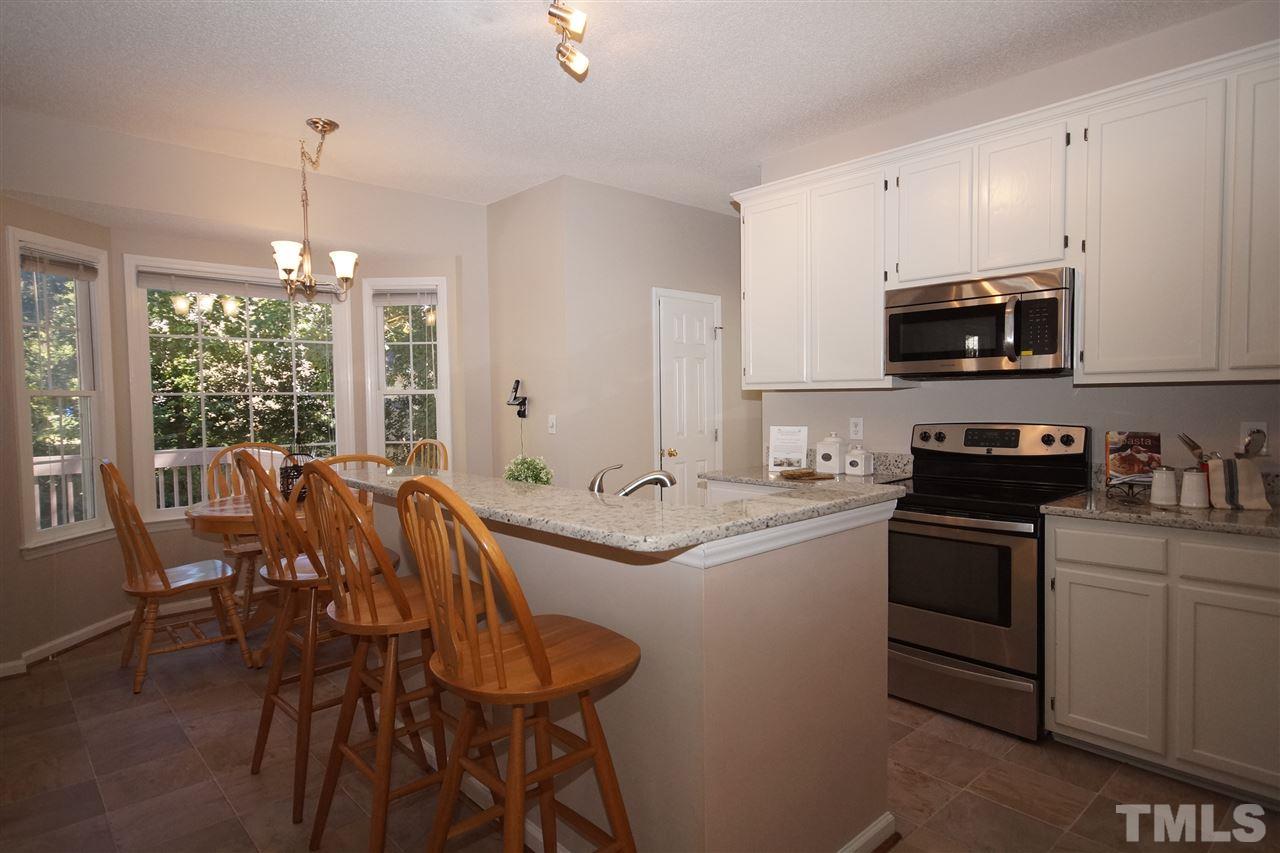 5249 Fairmead Circle Raleigh, NC 27613 - Photo 7 of 25 a kitchen with stainless steel appliances granite countertop a stove a sink a microwave a dining table and chairs with wooden floor