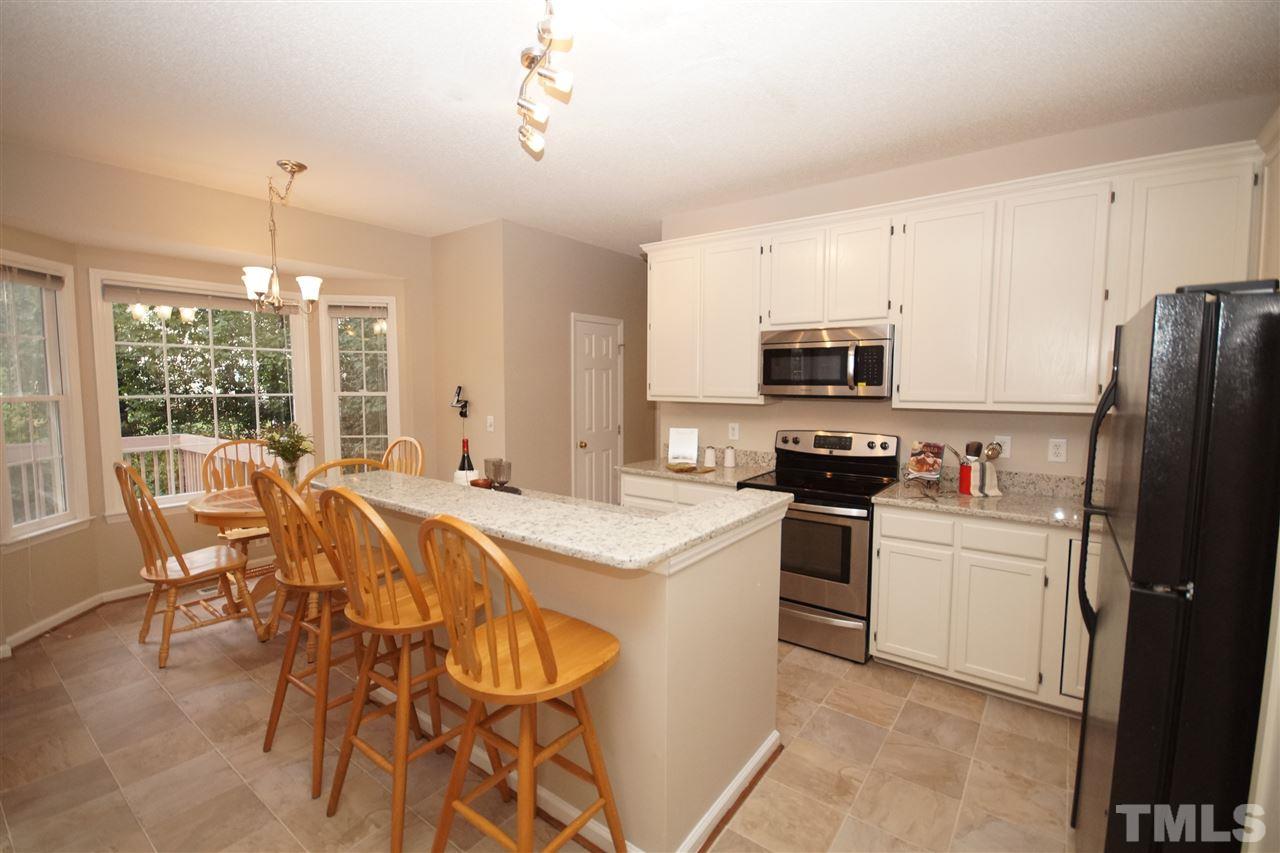 5249 Fairmead Circle Raleigh, NC 27613 - Photo 8 of 25 a kitchen with stainless steel appliances a stove a sink dishwasher a refrigerator and a dining table with chairs