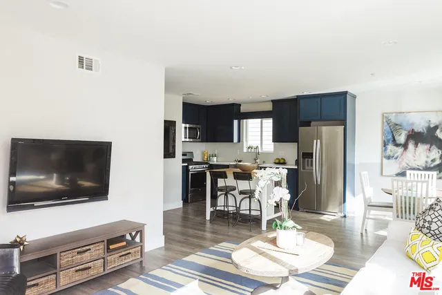 a kitchen with stainless steel appliances a dining table chairs refrigerator and sink