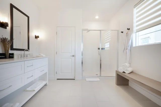 a spacious bathroom with a double vanity sink a large mirror and shower