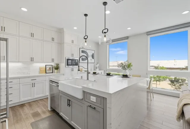 a kitchen with white cabinets and sink