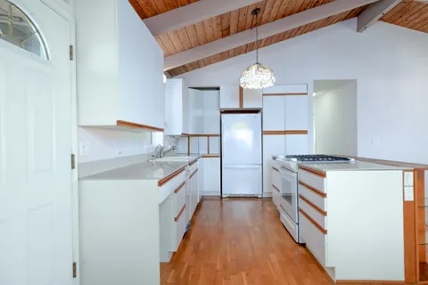 a view of empty room with wooden floor and window