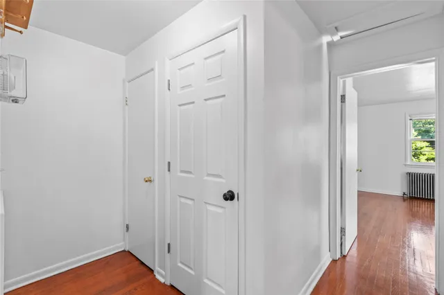 a view of a hallway with wooden floor and closet area