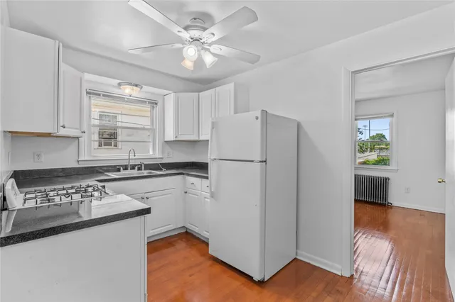 a kitchen with a refrigerator a stove cabinets and living room view