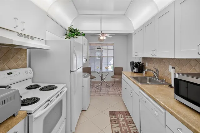 a kitchen that has a lot of white cabinets and stainless steel appliances