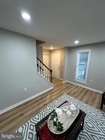 a living room with stainless steel appliances furniture a rug and a view of kitchen