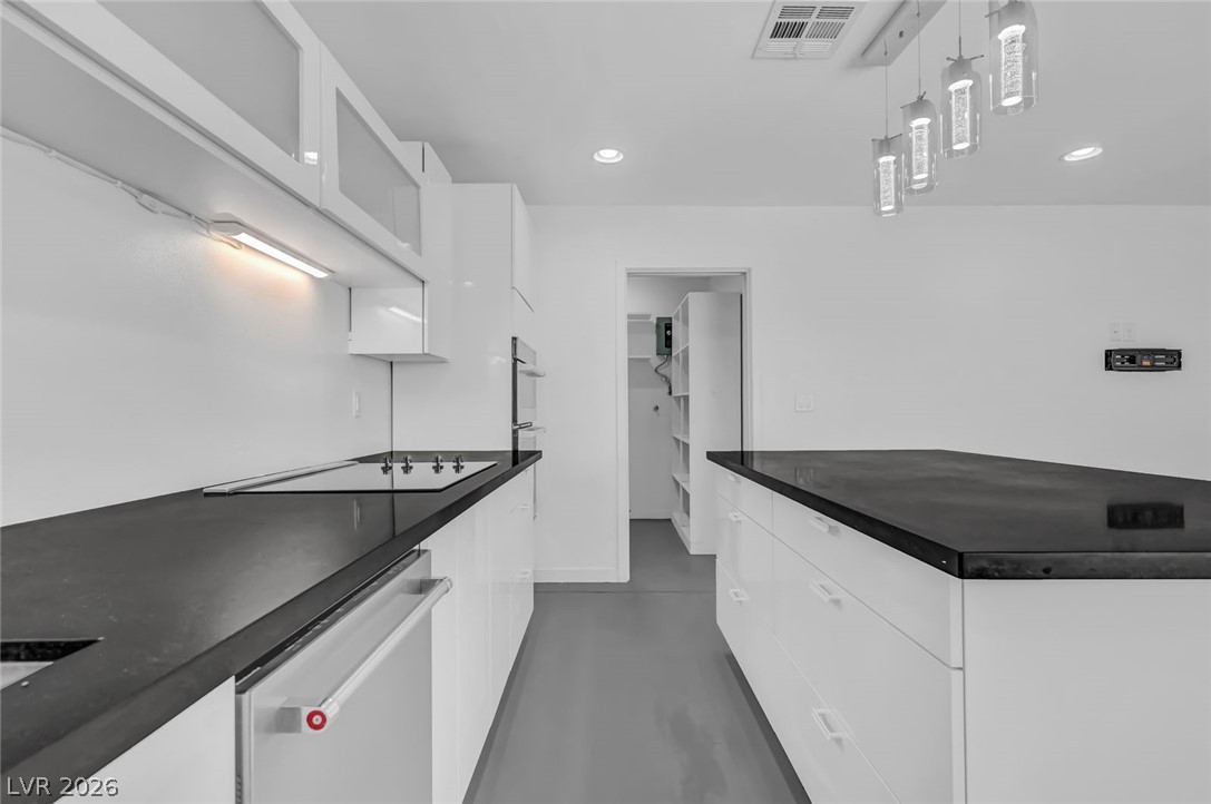 640 North Racetrack Road Henderson, NV 89015 - Photo 54 of 65 A streamlined kitchen showcases a sleek cooktop and abundant storage in minimalist white cabinetry.