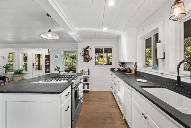 a kitchen with granite countertop stainless steel appliances a sink stove and cabinets