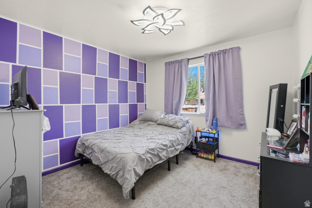 2135 East White Pine Road Eagle Mountain, UT 84005 - Photo 11 of 23 Room featuring a geometric accent wall, gray carpeting, and a window with purple drapes