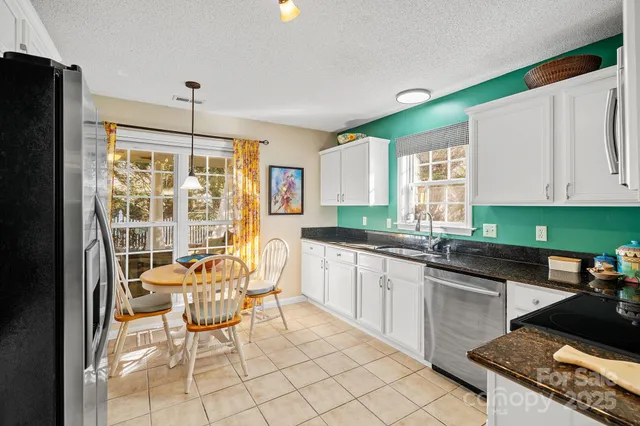a kitchen with granite countertop a sink a window and cabinets