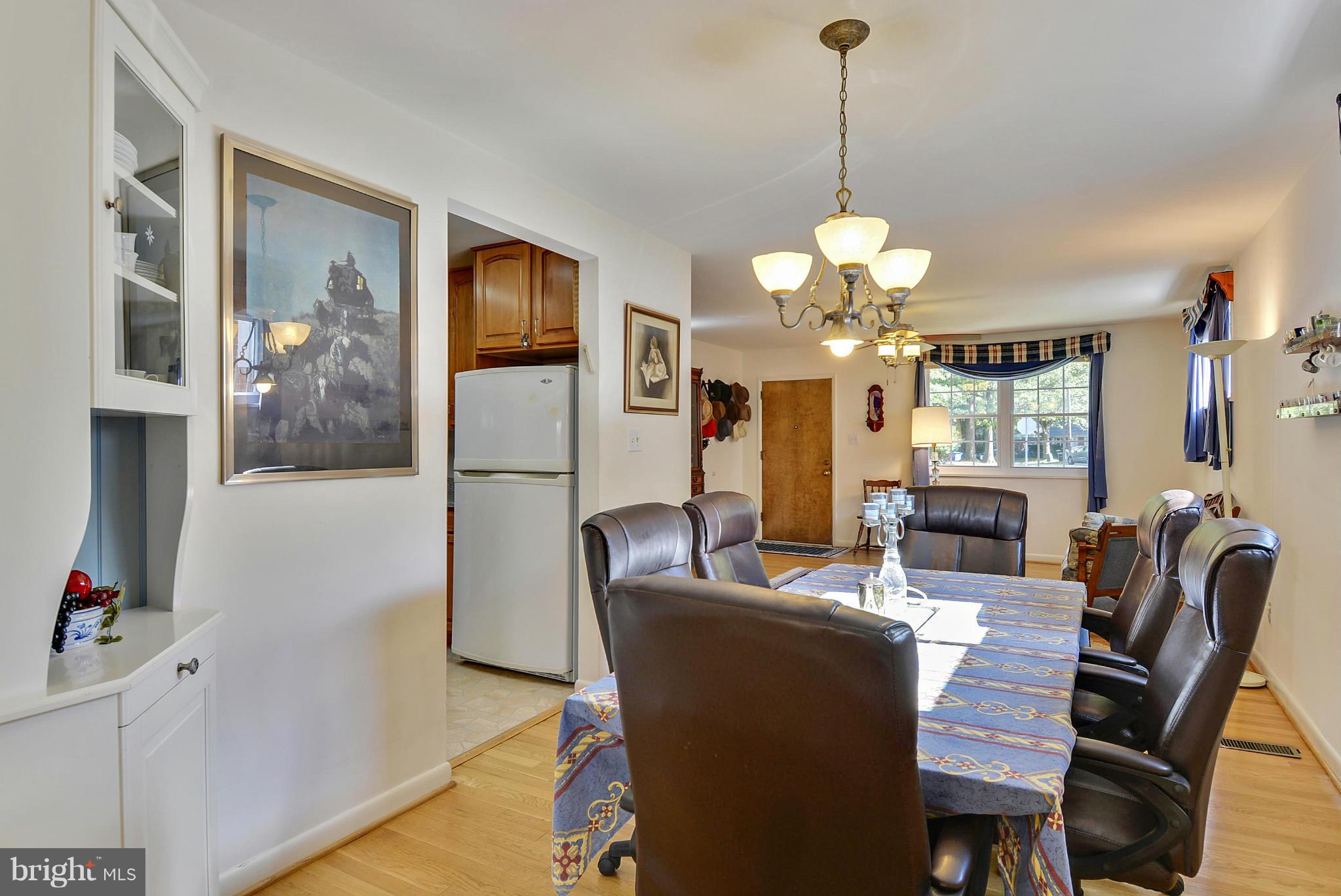 11113 Lombardy Road Silver Spring, MD 20901 - Photo 6 of 30 a dining room with wooden floor a chandelier a wooden table and chairs
