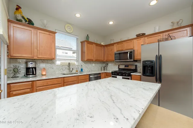 a kitchen with granite countertop a refrigerator sink and wooden cabinets