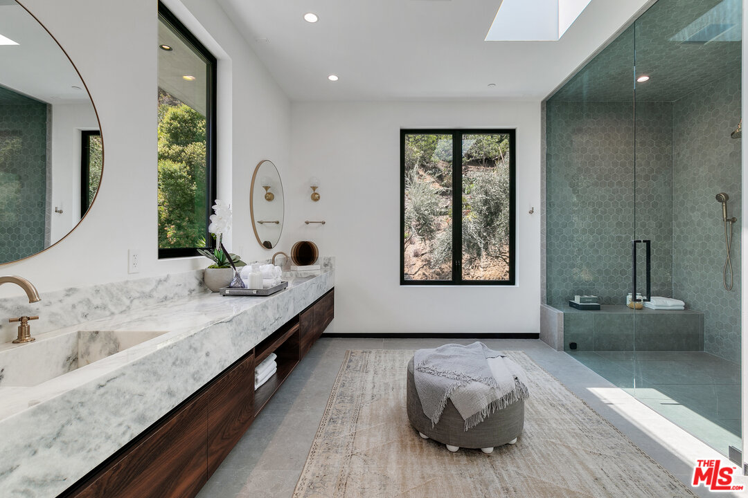 1461 Rising Glen Road Los Angeles, CA 90069 - Photo 16 of 22 a bathroom with a granite countertop tub a sink and a large mirror