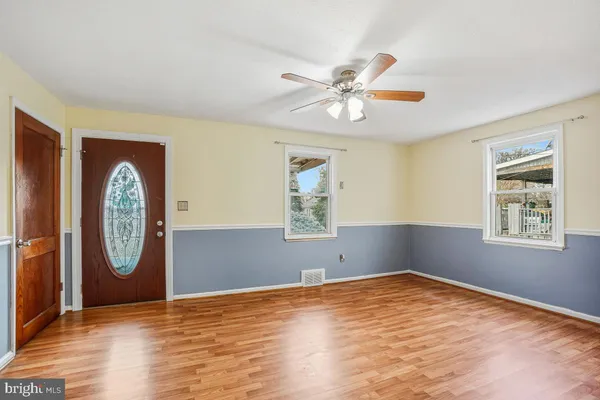 a view of empty room with wooden floor and fan